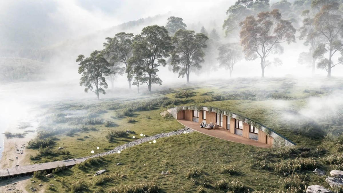 Podzemní dům zapuštěný do travnatého svahu, prosklená dřevěná fasáda s terasou nad jezerem v mlze.